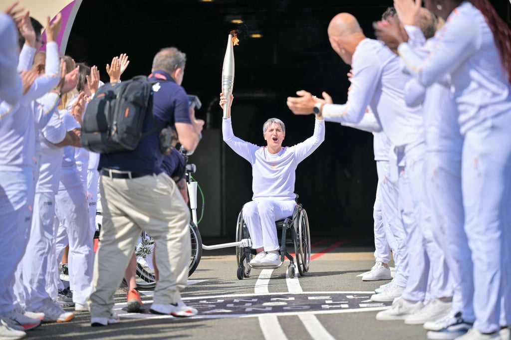 Emmanuelle Assmann, president of the French Paralympic and Sports Committee, holds the Paralympics torch after it arrives at the entrance of the Channel Tunnel in Coquelles, northern France. Photo: AFP